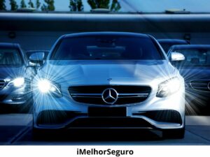 Mercedes-Benz prateado em destaque, com faróis acesos, em um estacionamento, exemplificando a importância dos melhores seguros para carros para uma proteção superior do veículo.